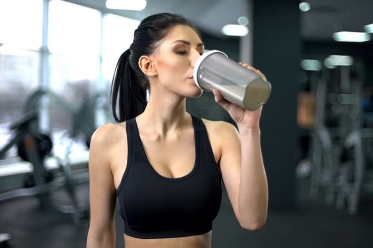 woman in gym drinking protein powder
